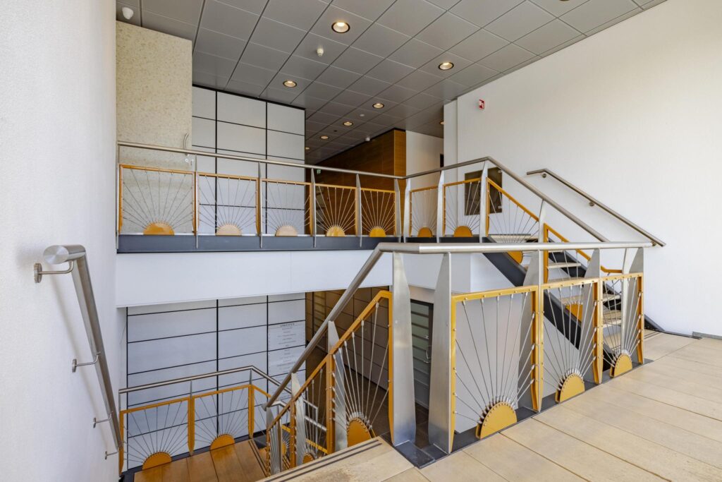 Trapruimte met modern metalen hekwerk en houten accenten in een kantoorgebouw aan de Joan Muyskenweg.